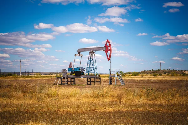 Bomba de óleo no campo em um céu nublado de fundo — Fotografia de Stock