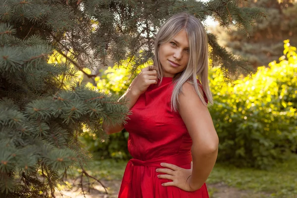 야외 공원에 빨간 이브닝 드레스에 포즈를 취하는 아름 다운 소녀 — 스톡 사진