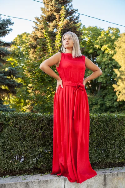 Hermosa chica posando en un vestido de noche rojo en el parque al aire libre —  Fotos de Stock