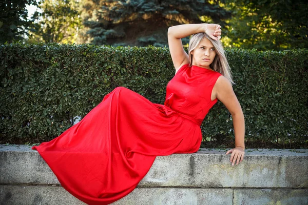 Красива дівчина позує в червоній вечірній сукні на відкритому повітрі — стокове фото
