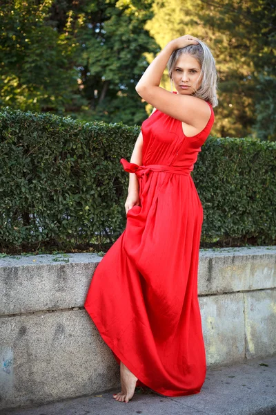 Menina bonita posando em um vestido de noite vermelho no parque ao ar livre — Fotografia de Stock