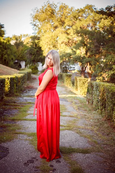 Hermosa chica posando en un vestido de noche rojo en el parque al aire libre —  Fotos de Stock