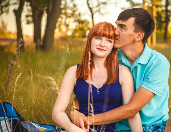 Hermosa pareja joven sentada en el campo; al aire libre —  Fotos de Stock