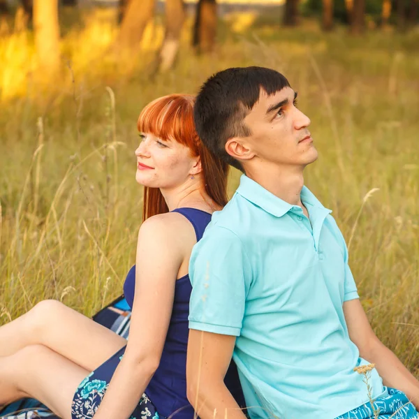 Vackra unga paret sitter i fältet. utomhus — Stockfoto