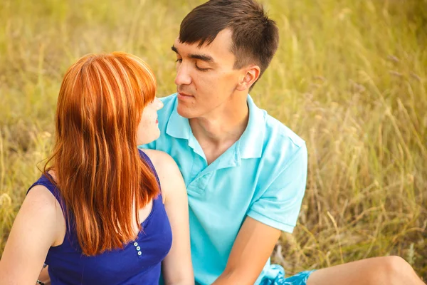 Красива молода пара сидить у полі; на відкритому повітрі — стокове фото