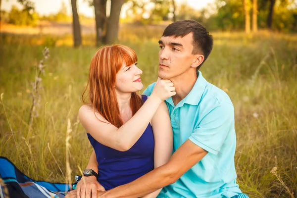 Vackra unga paret sitter i fältet. utomhus — Stockfoto