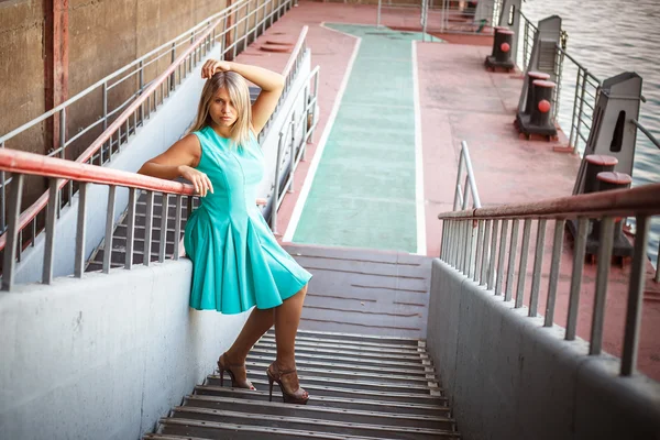 Young beautiful girl in a turquoise sundress posing on the steps — Stock Photo, Image