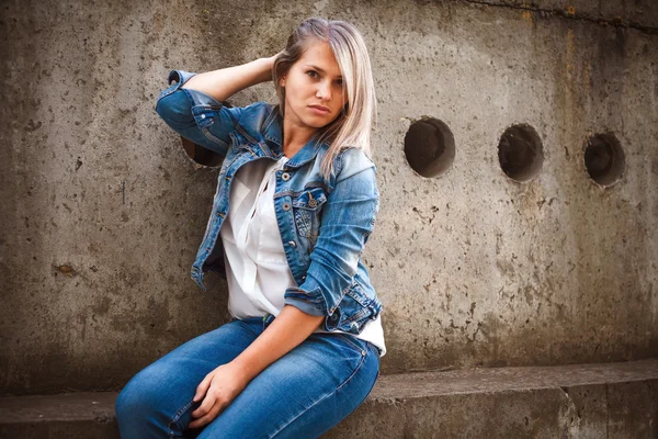 Hermosa chica en un traje de mezclilla posando en la ciudad al aire libre —  Fotos de Stock