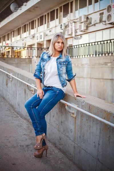 Hermosa chica en un traje de mezclilla posando en la ciudad al aire libre —  Fotos de Stock