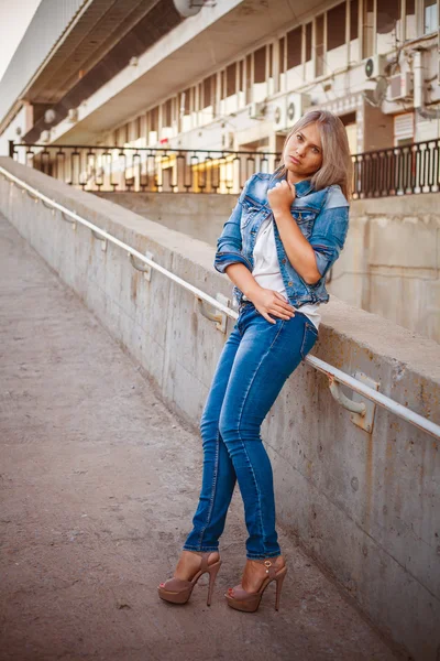 Hermosa chica en un traje de mezclilla posando en la ciudad al aire libre —  Fotos de Stock