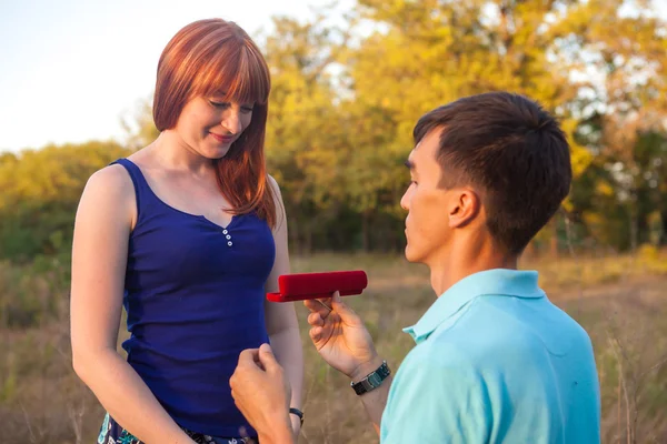 El chico le da a la chica una cadena en una caja en el bosque al aire libre —  Fotos de Stock