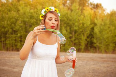 Dışarıda sabun köpüğü üfleyen genç bir kadın.