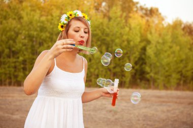 Dışarıda sabun köpüğü üfleyen genç bir kadın.