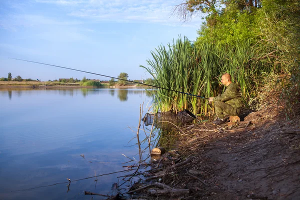 Hombre en traje de camuflaje es la pesca en el estanque — Foto de Stock
