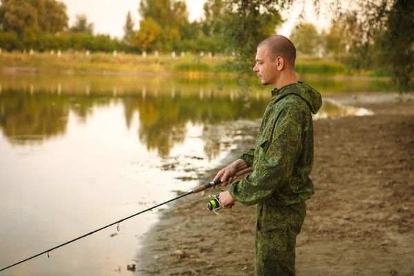 Hombre en traje de camuflaje es la pesca en el estanque — Foto de Stock