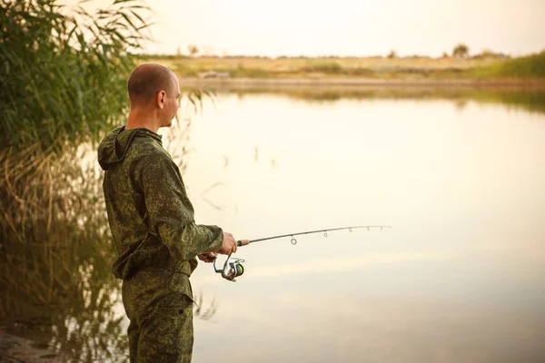 Hombre en traje de camuflaje es la pesca en el estanque — Foto de Stock