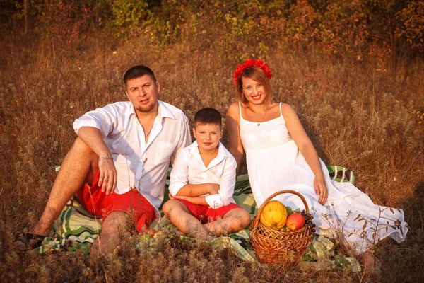 Mom dad and son sitting on a picnic rug in a park — Stock Photo, Image