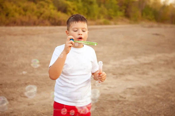 Pojken blåser såpbubblor i parken utomhus — Stockfoto
