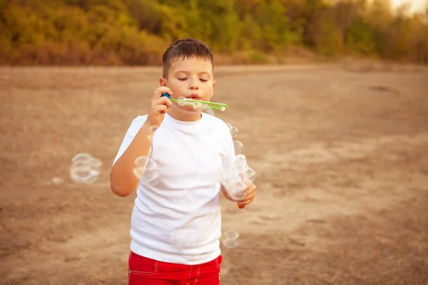 屋外の公園でシャボン玉を吹く少年 — ストック写真