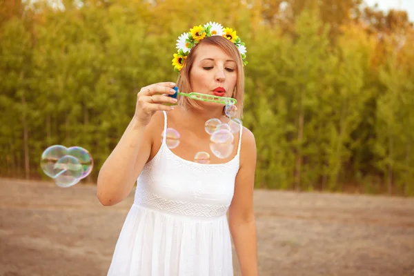 Mujer joven soplando burbujas de jabón al aire libre —  Fotos de Stock