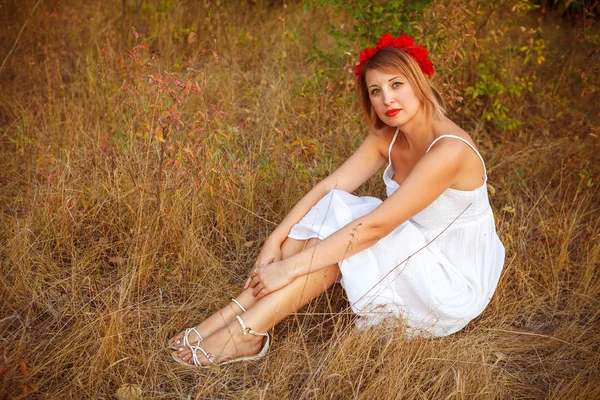 Mooie vrouw poseren zittend op een gebied; buitenshuis — Stockfoto