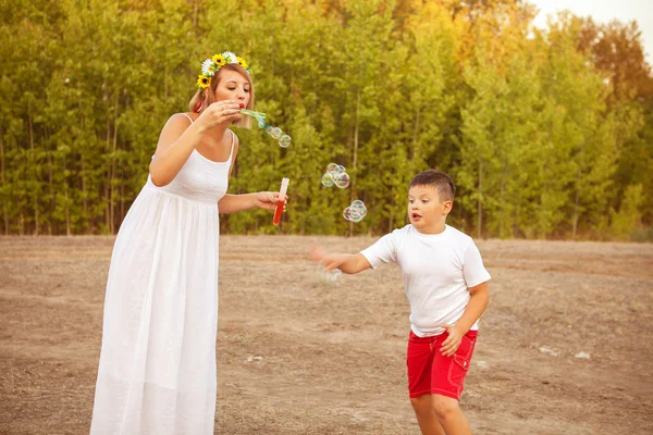 Mãe e filho sopram bolhas de sabão no parque para um passeio — Fotografia de Stock