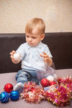 kanepede oturan Noel topları ile oynayan küçük çocuk