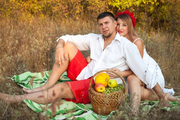 Husband and wife are sitting on the plaid in the park — Stock Photo, Image