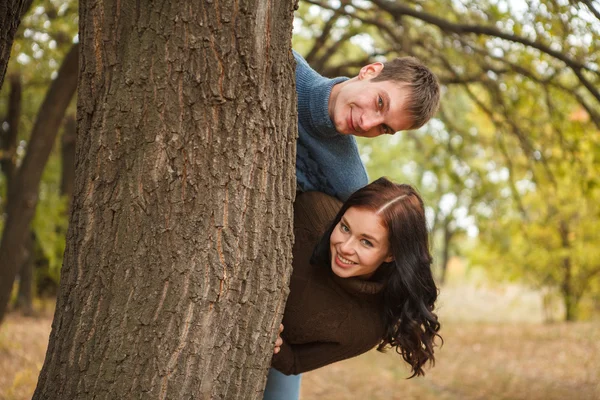 Pareja asomándose desde detrás de un árbol —  Fotos de Stock