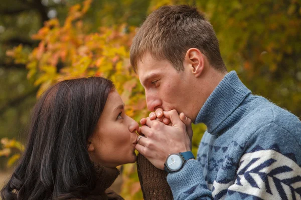 Hombre calienta sus manos chica respirando. El parque al aire libre — Foto de Stock