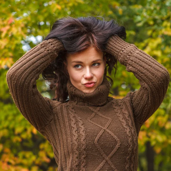 Menina bonita em um pulôver marrom posando no parque de outono — Fotografia de Stock