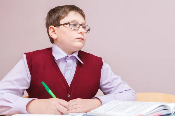 Niño con gafas sentado en un escritorio de escritura —  Fotos de Stock