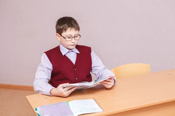 机に座って本を読む少年 — ストック写真