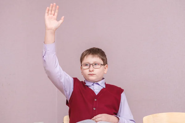 Boy pulls a hand up sitting at his desk — Stock Photo, Image