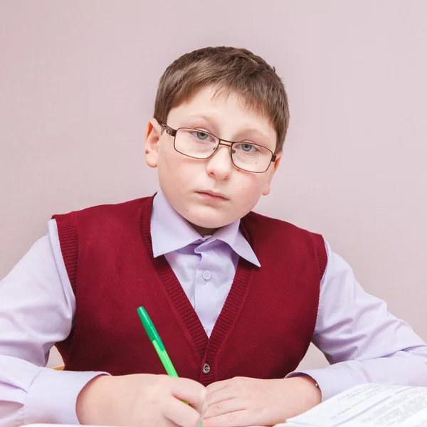 Niño con gafas sentado en un escritorio de escritura —  Fotos de Stock