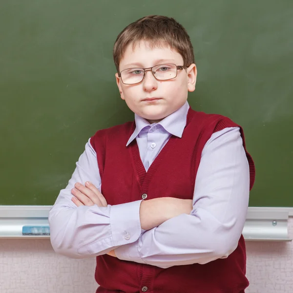 Pojken står med armarna korsade en skolans styrelse — Stockfoto