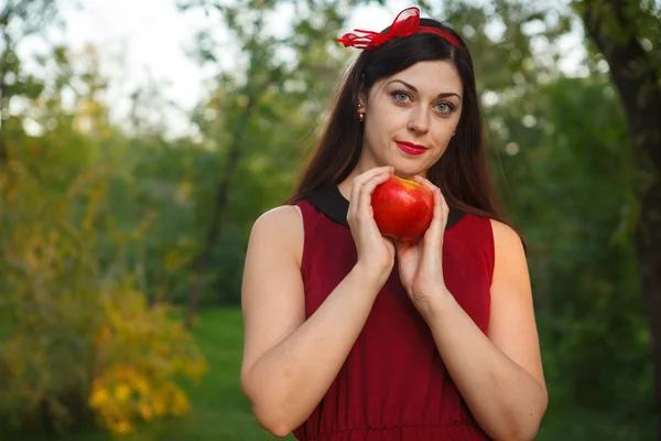 Красивая женщина позирует с яблоком в парке — стоковое фото