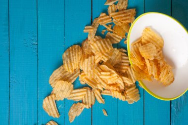 Patates cipsi plaka dışında mavi ahşap bir masa dökülür.