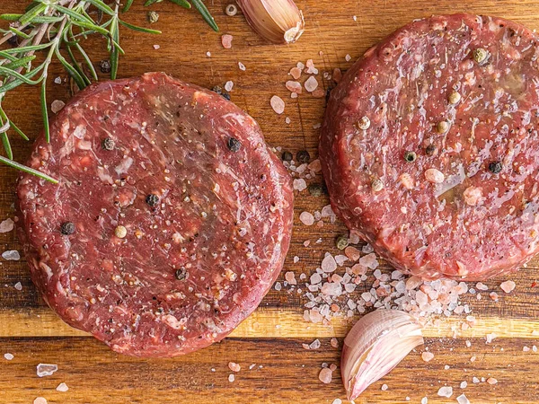 Hamburguesas de carne cruda sobre tabla de madera — Foto de Stock