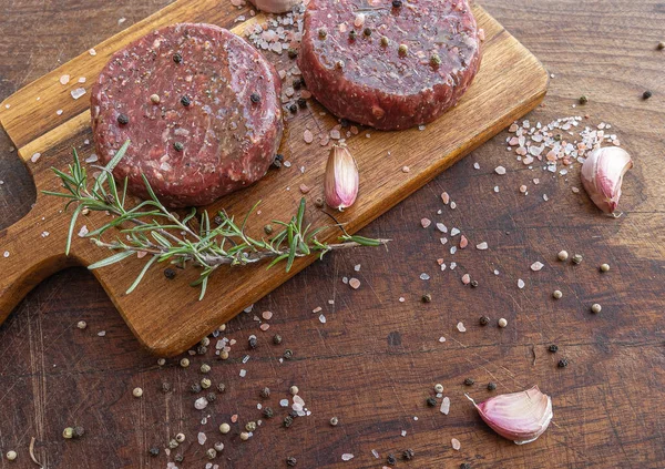 Hamburguesas de carne cruda sobre tabla de madera — Foto de Stock
