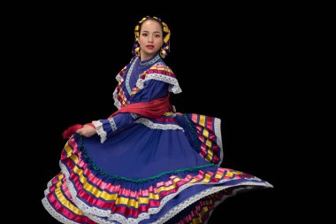 Jalisco Mexico 'dan gelen bir elbise giymiş Latin bir kadın. Parlak renkli kurdeleli mor bir çatışma. Örgülü, hareketli etekli, gülümseyen, siyah arka planlı.