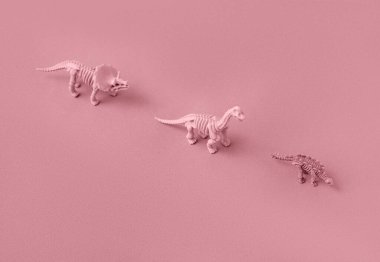 Pembe arka plandaki dinozor iskeletlerinin oyuncak modelleri.