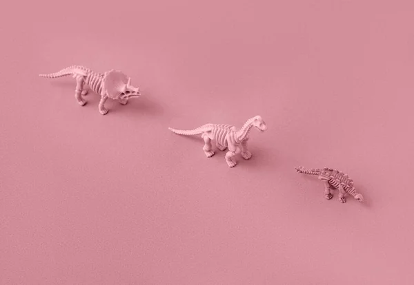 Pembe arka plandaki dinozor iskeletlerinin oyuncak modelleri.