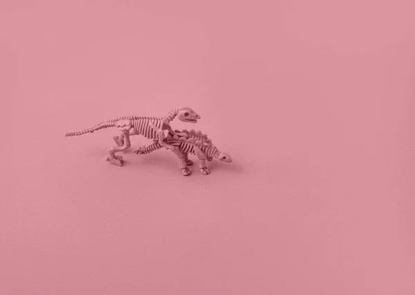 Pembe arka plandaki dinozor iskeletlerinin oyuncak modelleri.