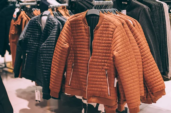 Kahverengi ve siyah ceketler süpermarkette askılarda asılı.