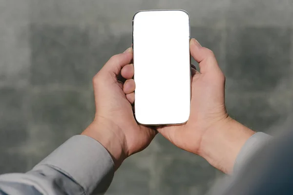 Kapatın, akıllı telefonu taklit edin, ellerde, bir insanın. beton bir duvarın arkasında.