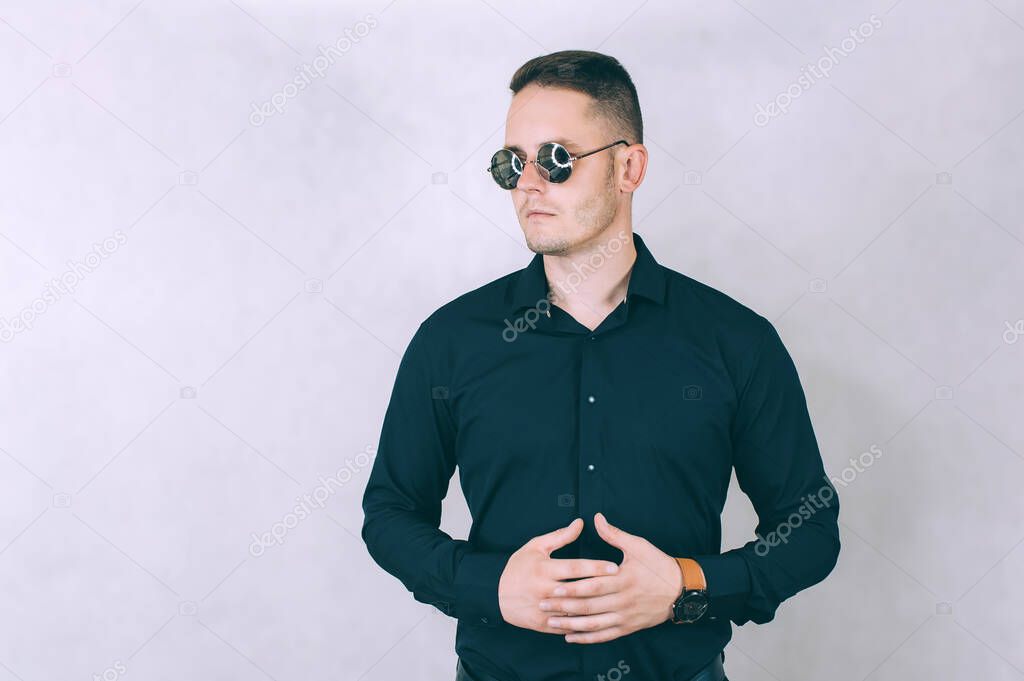 A business man in mirrored glasses and a shirt is standing in the studio. on a light background