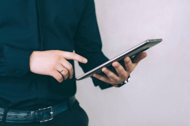 Adam parmağını tablet ekranın önünde tutuyor. Hafif bir arkaplanda