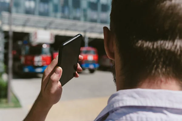 Yakından bir adam kurtarıcıları telefonla arıyor. İtfaiye araçlarının arka planında