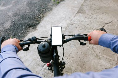 Yakın plan, bisikletin gidonundaki akıllı telefonun maketi. Beton ve asfaltın arka planına karşı